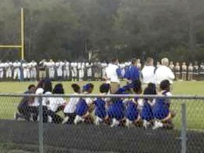 In this photo provided by Cary Lewis, members of the South Robeson High School cheerleading squad kneel during the national anthem before a football game Friday, Sept. 29, 2017, in Rowland, N.C. The decision by the school's cheerleaders to kneel drew both praise and strong criticism, often divided along racial lines. Though several cheerleaders have veterans in their families and meant no disrespect, many critics saw kneeling as a slap in the face to the military.  (Courtesy of Cary Lewis via AP)