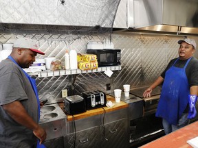 Mitch Addison, left, who is African-American and voted for Hillary Clinton, and co-worker Merle Fields, who is Native American and voted for Donald Trump, debate politics as they work in the kitchen of a diner in Lumberton, N.C., Saturday, Oct. 28, 2017. They stand at the grill, shoulder-to-shoulder, as the breakfast rush wanes and the customers start to clear out. Fields seizes on this slow moment to discuss his favorite topic: Donald Trump. "I agree with him: Let's make America great again," he declares. Addison looks over at him and cocks an eyebrow. "This is great?" he asks. "America is not so great right now."