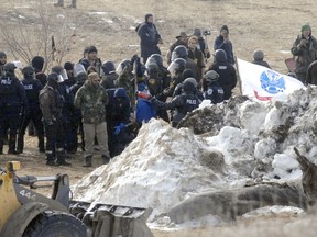 FILE - In this Feb. 23, 2017 file photo, law enforcement enters the Oceti Sakowin camp to begin arresting Dakota Access oil pipeline protesters in Morton County, near Cannon Ball, N.D. North Dakota law enforcement purchased more than $600,000 worth of body armor, tactical equipment and crowd control devices during the height of protests against the Dakota Access oil pipeline, state invoices show.