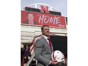 New Nebraska head NCAA college football coach Scott Frost poses at Memorial Stadium with a football helmet following a news conference in Lincoln, Neb., Sunday, Dec. 3, 2017. Frost is returning to Nebraska after orchestrating a stunning two-year turnaround at Central Florida.