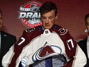 In this June 23, 2017 file photo, Cale Makar pulls on a Colorado Avalanche jersey after being selected fourth overall in the NHL draft.