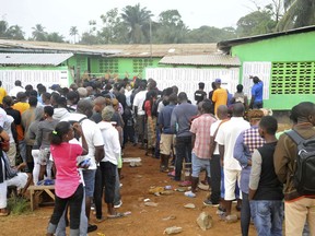 People wait to cast their votes during a Presidential runoff election in Monrovia, Liberia, Tuesday, Dec. 26, 2017. Young Liberians went straight from all-night Christmas celebrations to the polls Tuesday for a runoff election between a former international soccer star and the vice president to replace Africa's first female head of state.
