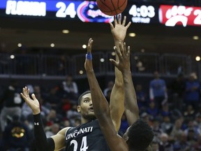 Cincinnati's Kyle Washington (24) takes a shot past Florida's Keith Stone (25) and Kevarrius Hayes (13) during the first half of an NCAA college basketball game Saturday, Dec. 9, 2017, in Newark, N.J.