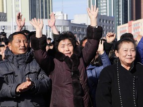 People cheer as they watch the news broadcast announcing North Korean leader Kim Jong Un's order to test-fire the newly developed inter-continental ballistic missile Hwasong-15, Wednesday, Nov. 29, 2017, at the Pyongyang Train Station in Pyongyang, North Korea.