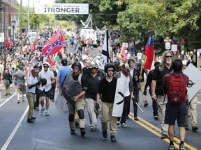 FILE - In this Aug. 12, 2017 file photo, White nationalist demonstrators walk through town after their rally was declared illegal near Lee Park in Charlottesville, Va. A former federal prosecutor says the law enforcement response to a white nationalist rally this summer in Charlottesville that erupted in violence was a series of failures. The findings of former U.S. Attorney Tim Heaphy's monthslong investigation were unveiled Friday, Dec. 1. City officials asked him to conduct the review after facing scathing criticism over the Aug. 12 rally.