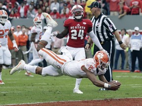 FILE - In this Nov. 4, 2017, file photo, Clemson quarterback Kelly Bryant (2) dives into the end zone for a touchdown while North Carolina State's Shawn Boone (24) looks on during the first half of an NCAA college football game, in Raleigh, N.C. Clemson will likely have a quarterback, two wide receivers and a running back starting their first playoff game at the Sugar Bowl against Alabama. But coach Dabo Swinney thinks Clemson's wins at Virginia Tech, Louisville and North Carolina State and a likely playoff elimination game in the ACC championship show the 2017 Tigers can handle the pressure.