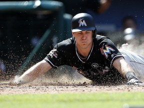 FILE - In this Aug. 24, 2017, file photo, Miami Marlins' J.T. Realmuto dives into home plate with a with a two-run inside the park home run against the Philadelphia Phillies during the sixth inning of a baseball game, in Philadelphia, Pa. A person familiar with the situation says Miami Marlins catcher J.T. Realmuto has requested a trade in the wake of the team's latest payroll purge. The person confirmed the request to The Associated Press on condition of anonymity Monday, Dec. 18, 2017, because the Marlins didn't comment.