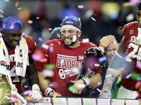 FILE - In this Dec. 2, 2017, file photo, Oklahoma quarterback Baker Mayfield, center, holds his Most Outstanding Player trophy as he celebrates with the team after their 41-17 win in the the Big 12 Conference championship NCAA college football game against TCU, in Arlington, Texas. Baker Mayfield is the AP player of the year, becoming the fourth Oklahoma quarterback to win the award since it was established in 1998.