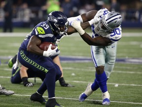 File- This Dec. 24, 2017, file photo shows Seattle Seahawks running back Mike Davis (39) fighting off a tackle attempt by Dallas Cowboys' DeMarcus Lawrence (90) in the second half of an NFL football game in Arlington, Texas. Dallas has pegged him as its next great pass rusher, and he came through in style this season with 14½ sacks. He's the kind of player to build a defensive line around.