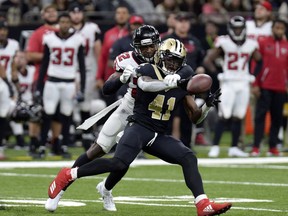 FILE - In this Dec. 24, 2017, file photo, Atlanta Falcons strong safety Keanu Neal (22) tries to break up a pass intended for New Orleans Saints running back Alvin Kamara (41) during the first half of an NFL football game in New Orleans. Kamara says the NFL has fined him $6,079 for wearing Christmas-themed red cleats with white trim during last Sunday's victory over Atlanta. Kamara says it was worth it and says he's hoping to parlay publicity from his banned holiday cleats into a fundraiser to help supply athletic footwear to children whose families struggle to afford it.