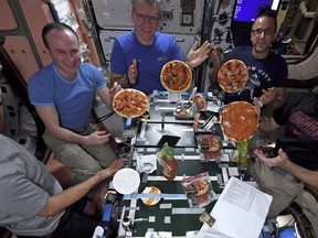 In this Nov. 18, 2017 photo provided by NASA, from left, American Mark Vande Hei, Russian Sergei Ryazanskiy, Italian Paolo Nespoli, American Joe Acaba and American Randy Bresnik display the results of their made-from-scratch pizza pies at the International Space Station. The fixings flew up in November on a commercial supply ship. (NASA via AP)