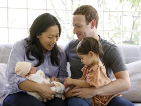 FILE - This file photo provided Monday, Aug. 28, 2017, by Facebook, shows Facebook CEO Mark Zuckerberg with his wife, Priscilla Chan, and their new baby daughter August, left, and her sister Maxima, right, in Palo Alto, Calif. Zuckerberg says he is taking parental leave for the month of December to spend more time with his daughters.