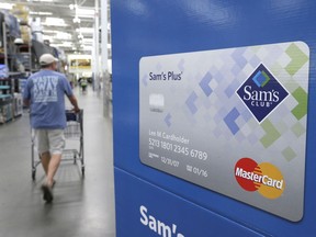 FILE - In this Thursday, June 4, 2015, file photo, a customer walks past a sign promoting the Sam's Club Mastercard credit card at a Sam's Club store store in Bentonville, Ark. Saving money on holiday purchases now by opening a store credit card could cost you later in credit score points.
