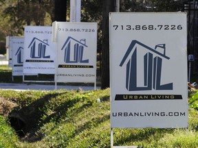 FILE - In this Tuesday, Feb. 16, 2016, file photo, "For Sale" signs are stacked up outside a complex of townhouses in Houston. On Thursday, Dec. 21, 2017, Freddie Mac reports on the week's average U.S. mortgage rates.