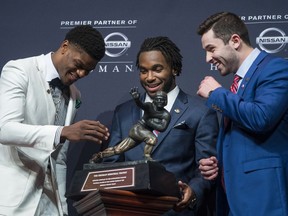 Heisman Trophy finalists, from left, Louisville quarterback Lamar Jackson, Stanford running back Bryce Love and Oklahoma quarterback Baker Mayfield look at the trophy during a media event Saturday, Dec. 9, 2017, before the final selection in New York.