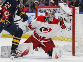 Carolina Hurricanes goalie Cam Ward, right, makes a glove-save during the first period of an NHL hockey game against the Buffalo Sabres, Friday Dec. 15, 2017, in Buffalo, N.Y.