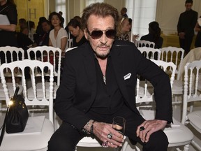 In this July 4, 2016 picture, French rock singer Johnny Hallyday waits before Christian Dior's Haute Couture Fall-Winter 2016-2017 fashion collection presented in Paris, France. The French president's office says Hallyday, who packed sports stadiums for decades, has died at age 74.