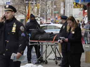 Police remove the body of a man following an incident, Sunday, Dec. 3, 2017, in the Queens borough of New York. Authorities are searching for a driver who struck a group of people, leaving at least one dead.