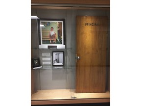 This Dec. 20, 2017, photo provided by Cambridge Central Schools shows a display case with photos, an illustration and the door that was once on the Principal's office at Cambridge Central Schools in Cambridge, N.Y. Inside the case is the original door from the principal's office that served as the setting for the Normal Rockwell Saturday Evening Post cover in 1953, known as "Girl With Black Eye," or "The Shiner." Steve Butz, a science teacher at Cambridge High School, preserved the door for display after it was replaced during a renovation project.