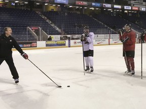 In this Dec. 12, 2017 photo, Team Canada assistant coach Tim Hunter, left, addresses players who hope to make the World Juniors Team on the first day of Team Canada's selection camp at St. Catharines, Ontario. From center left is Cale Makar, Dennis Cholowski and Josh Mahura. The 10-nation tournament is being played at Buffalo, N.Y., and opens on Tuesday, Dec. 26. It will feature Canada and the U.S. playing an outdoor game at the NFL Buffalo Bills' New Era Field on Friday, Dec. 29.
