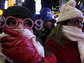 FILE- In this Dec. 31, 2008 file photo, Allison Smith of Jacksonville, Fla, left, tries to keep warm as she and others take part in the New Year's Eve festivities in New York's Times Square. Brutal weather has iced plans for scores of events in the Northeast U.S. from New Year's Eve through New Year's Day, but not in New York City, where people will start gathering in Times Square up to nine hours before the famous ball drop.