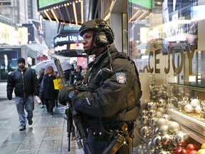 FILE - In this Dec. 29, 2016 file photo, a heavily armed counterterrorism officer takes shelter beneath an overhang above a store in Times Square in New York. New York Police Department officials say that while there are no specific or credible threats against the city, they are promising a bigger security detail than ever before at the Sunday, Dec. 31, 2017, New Year's Eve celebration in Times Square.