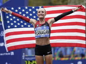File- This Nov. 5, 2017, file photo shows Shalane Flanagan of the United States posing for pictures after crossing the finish line first in the women's division of the New York City Marathon in New York.   Flanagan will run in Boston next year in a fourth attempt to win her hometown race. The four-time Olympian and reigning Chicago Marathon champion will be joined on the men's side by Galen Rupp in a field of elite Americans announced Monday, Dec. 11, 2017, by race sponsor John Hancock. Olympians Desiree Linden, Dathan Ritzenhein, Abdi Abdirahman, Deena Kastor and Molly Huddle also are signed up for the 122nd edition of the world's oldest annual marathon, which is being held April 16.