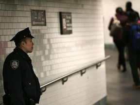 Police officers patrol in the passageway connecting New York City's Port Authority bus terminal and the Times Square subway station Tuesday, Dec. 12, 2017, near the site of Monday's explosion. Commuters returning to New York City's subway system on Tuesday were met with heightened security a day after a would-be suicide bomber's rush-hour blast failed to cause the bloodshed he intended.