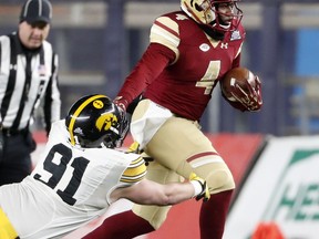 Boston College quarterback Darius Wade (4) fends off a tackle by Iowa defensive lineman Brady Reiff (91) during the first quarter of the Pinstripe Bowl NCAA college football game, Wednesday, Dec. 27, 2017, in New York.