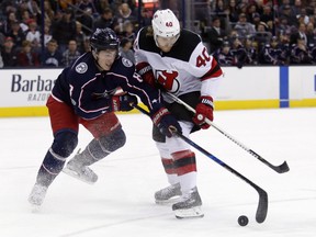 Columbus Blue Jackets defenseman Zach Werenski, left, reaches for the puck against New Jersey Devils forward Blake Coleman during the first period of an NHL hockey game in Columbus, Ohio, Tuesday, Dec. 5, 2017.