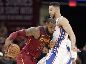 Cleveland Cavaliers' LeBron James, left, drives past Philadelphia 76ers' Ben Simmons during the first half of an NBA basketball game, Saturday, Dec. 9, 2017, in Cleveland.