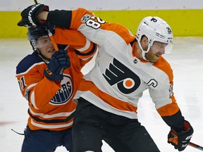 Claude Giroux of the Phialdelphia Flyers checked by the Oilers' Drake Caggiula during the second period of their game in Edmonton on Wednesday night.
