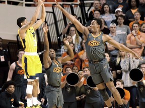 West Virginia guard James Bolden (3) takes a shot at the basket over Oklahoma State defenders guard Brandon Averette (0) and forward Cameron McGriff (12) in the first half of an NCAA college basketball game in Stillwater, Okla., Friday, Dec. 29, 2017.