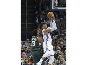 Oklahoma City Thunder guard Russell Westbrook (0) shoots two points as he slides past Milwaukee Bucks guard Malcolm Brogdon (13) during the first half of an NBA basketball game in Oklahoma City, Friday, Dec. 29, 2017.