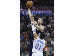 Denver Nuggets center Mason Plumlee, top, shoots over Oklahoma City Thunder guard Andre Roberson (21) in the first quarter of an NBA basketball game in Oklahoma City, Monday, Dec. 18, 2017.