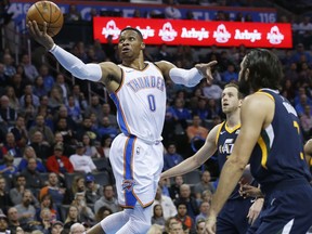 Oklahoma City Thunder guard Russell Westbrook (0) shoots in front of Utah Jazz forward Joe Ingles, center, and guard Ricky Rubio, right, during the first quarter of an NBA basketball game in Oklahoma City, Wednesday, Dec. 20, 2017.