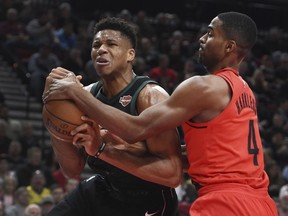 Milwaukee Bucks forward Giannis Antetokounmpo is tied up for a jump ball by Portland Trail Blazers forward Maurice Harkless, right, during the first quarter of an NBA basketball game in Portland, Ore., Thursday, Nov. 30, 2017. (AP Photo/Steve Dykes)