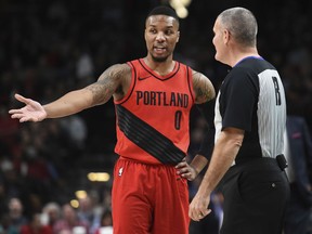 Portland Trail Blazers guard Damian Lillard has some words with referee Monty McCutchen during the first half of an NBA basketball game against the Washington Wizards in Portland, Ore., Tuesday, Dec. 5, 2017.