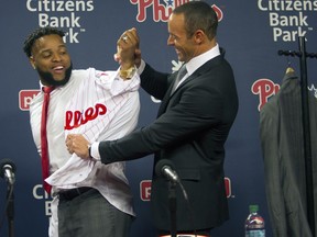 Philadelphia Phillies manager Game Kapler, right, helps newly signed first baseman Carlos Santana put on his jersey as he was introduced to the media during a baseball press conference at Lincoln Financial Field in Philadelphia, Wednesday, Dec. 20, 2017. Jr