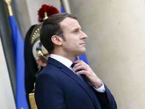 FILE - In this Dec.19, 2017 file photo, French President Emmanuel Macron adjusts his tie at the Elysee Palace, in Paris. As Macron turns 40 Thursday, he's wrapping up a remarkable year. In the seven months since he won a long-shot presidential bid, he has proved to be a key leader in Europe and in the world, at the forefront of the battles against terrorism and climate change and mediating in crises around the Middle East. Now the hard part: transforming France, where critics brand him an arrogant monarch.