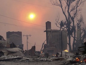 The sun breaks through dense smoke over fire-damaged structures in Ventura, Calif., Tuesday, Dec. 5, 2017. Ferocious Santa Ana winds raking Southern California whipped explosive wildfires Tuesday, prompting evacuation orders for thousands of homes.
