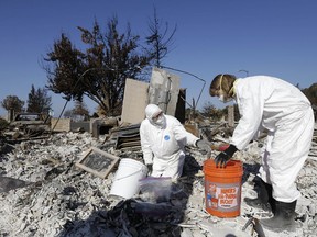 FILE - In this Tuesday, Oct. 31, 2017 file photo, David Rust, left, and his wife Shelly search through the remains of their home destroyed by wildfires in Santa Rosa, Calif. More than $9 billion in insurance claims have been filed following wildfires that ravaged Northern California two months ago, the state's top insurance regulator said Wednesday, Dec. 6, 2017.