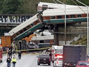 FILE - In this Dec. 18, 2017, file photo, cars from an Amtrak train lie spilled onto Interstate 5 below alongside smashed vehicles as some train cars remain on the tracks above in DuPont, Wash. Federal investigators say video aboard the Amtrak train that derailed in Washington state shows crews weren't using personal electronic devices and that the engineer remarked about the speed six seconds before the train went off the tracks south of Seattle.