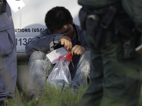 FILE - In this Aug. 11, 2017, file photo, an immigrant suspected of crossing into the United States illegally along the Rio Grande near Granjeno, Texas, is held by U.S. Customs and Border Patrol agents. The U.S. government posted a seventh straight monthly increase in people being arrested or denied entry along the Mexican border, erasing much of the early gains of President Donald Trump's push to strengthen border security.