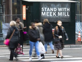 People walk past a placard posted on a newsstand with a message of support for imprisoned rapper Meek Mill, in Philadelphia, Friday, Dec. 1, 2017.  Mill's imprisonment on a probation violation has set off a flurry of legal appeals, criticism of the criminal justice system, newspaper opinion pieces, rallies, billboards and bus ads.