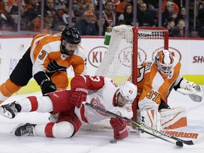 Detroit Red Wings' Darren Helm (43) loses the puck against Philadelphia Flyers' Radko Gudas (3) and Brian Elliott (37) during the first period of an NHL hockey game, Wednesday, Dec. 20, 2017, in Philadelphia.