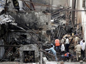 Indian fire officials inspect the burnt down shop in Mumbai, Monday, Dec. 18, 2017. Indian media reports say an overnight fire in Mumbai has killed 12 workers sleeping at a small shop that made and sold fried snacks.