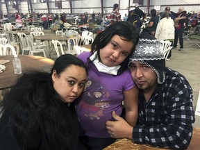 Wildfire survivors, Marolyn Romero-Sim, left, with Hugo Romero-Rodriguez, middle, and their 9-year-old daughter, Milagros, sit inside the evacuation center at the Ventura County Fairgrounds in Ventura, Calif. Their RV burned up with all their possessions in Ventura, Calif. Wind-driven fires have raced through California communities for the second time in two months, leaving hundreds of homes feared lost and uprooted tens of thousands of people. The most damaging fire is in Ventura County northwest of Los Angeles, where more than 100 square miles (259 sq. kilometers) and numerous homes have burned.