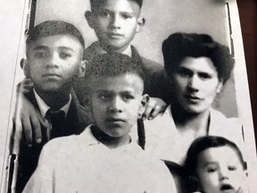 This photo taken in Nogales, N.M., on Dec. 5, 2017, shows a 1944 photograph of Arizona border Sheriff Tony Estrada's family, who were required by U.S. officials for a crossing document allowing them to pass from Mexico to the United States, where they legally settled later that year. Sheriff Estrada of Santa Cruz County is shown in the lower right-hand corner as a toddler and the youngest of four boys. He is held by his mother, Maria Guadalupe Lizarraga, and flanked by his older brothers Octavio Estrada, on the top, Jesus Estrada, on the far left, and Hector Estrada, in the white shirt in the front. A fifth boy, Ricardo Estrada, was later born in the United States, where they settled with their father and Lizarraga's husband, Jesus Estrada. Sheriff Estrada's opinions on immigration were shaped by being born in Mexico and immigrating with his family to the United States (Courtesy of Tony Estrada via AP)