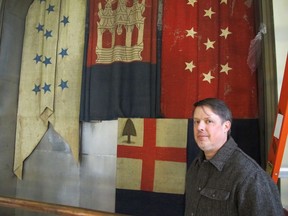 In this Thursday, Dec. 7, 2017 photo, Charles Swift, managing director and curator of the U.S. Naval Academy Museum, stands in front of a case in Annapolis, Md., where the flags shown behind him had been tucked away from view behind another flag on display for nearly 100 years. The flags were recently moved out of the cases for preservation.